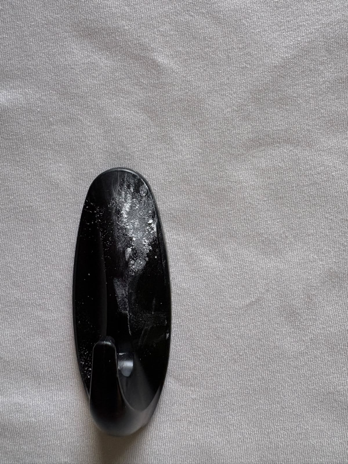 Pieza manufacturada negra con manchas blancas visibles en su superficie, defecto clasificado como manchada por VisionQA